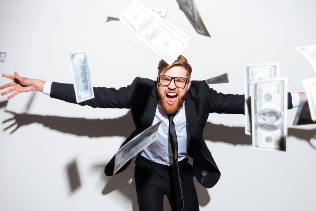 a bearded business man in a suit and glasses with falling money and arms outstretched
