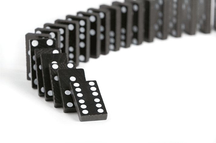 dominoes falling in a line to represent the damaging effects of pipeline bloat