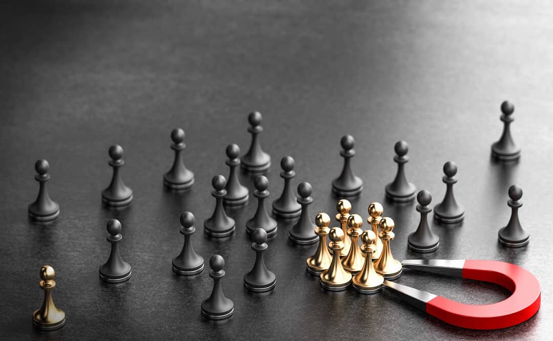 Inbound marketing concept: Horseshoe magnet attracting golden pawns over black background
