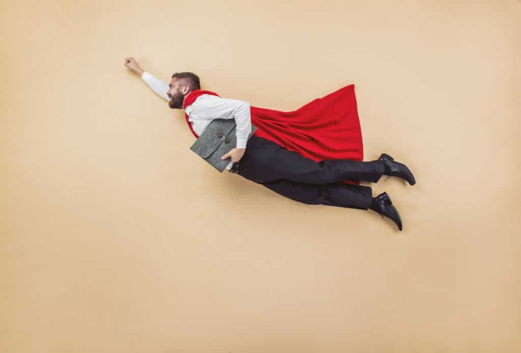 manager in a superman pose wearing a red cloak studio to represent success